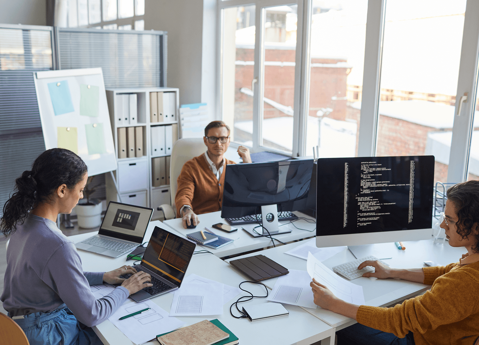 Team working at desks with multiple monitors, dedicated team engagement model